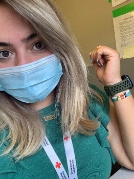 A young woman in mask and scrubs wearing Red Cross lanyard