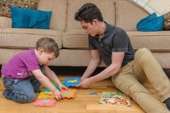 A man and a young child sorting colourful squares on the floor