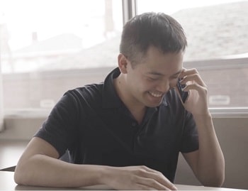 A man smiling while talking on a phone