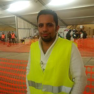 A man in a yellow vest smiling at the camera
