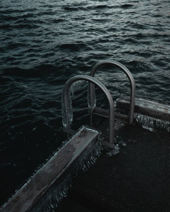 A frozen dock ladder with dark waters moving past