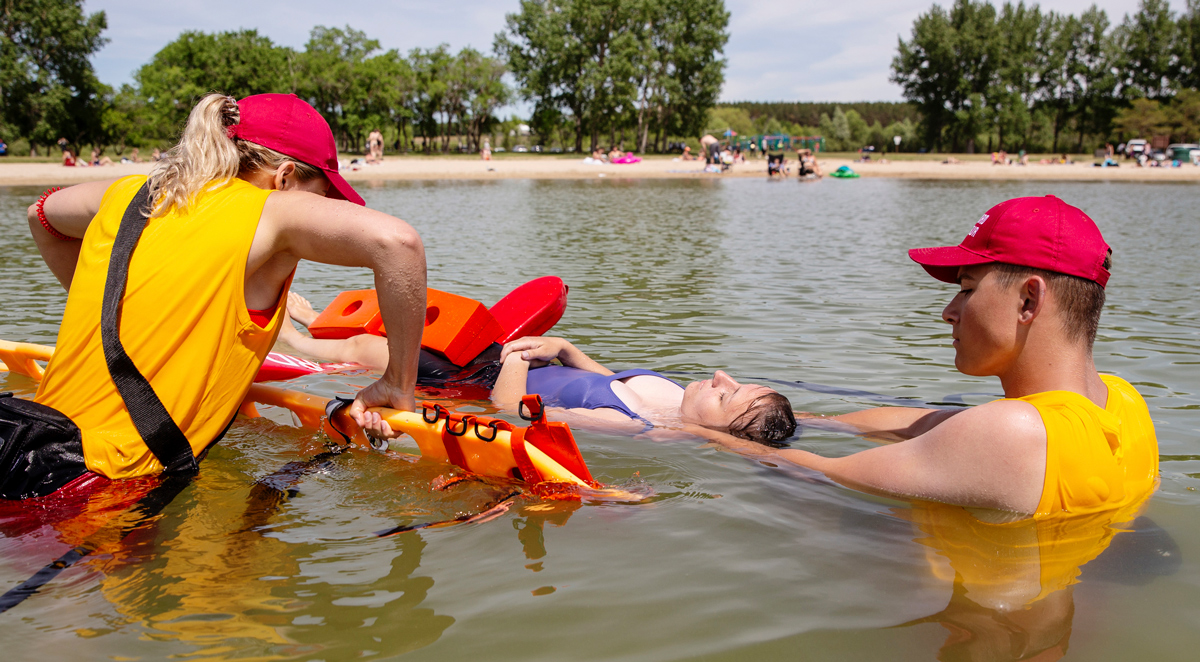 Two lifeguards preforming a life saving exercise on a person floating in a lake.