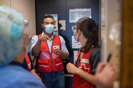 Two Red Cross volunteers mid-conversation inside of a Hospital.