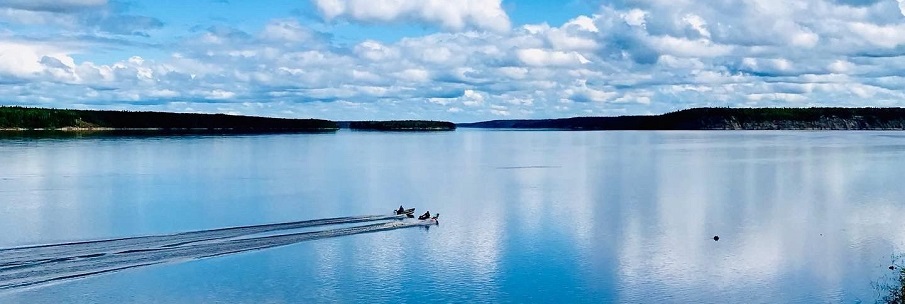 Two boats driving on a very picturesque lake