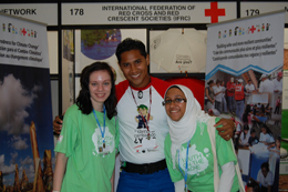 Three people pose for a photo smiling, at a IFRC convention