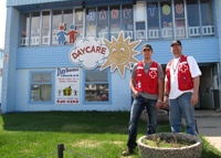 Two Canadian Red Cross volunteers in front of one of a day care