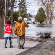 Red Cross volunteer and man standing by flood waters