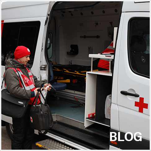 A Ukranian Red Cross staff member standing next to a mobile health unit in Mytlashivka