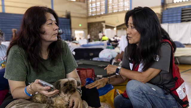 Women recalls fleeing the fires with a Red Cross volunteer at the Red Cross shelter in Wailuku, Maui