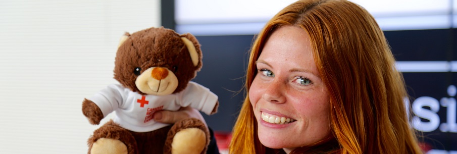 A closeup of a Red Cross volunteer presenting a Canadian Red Cross teddy bear.