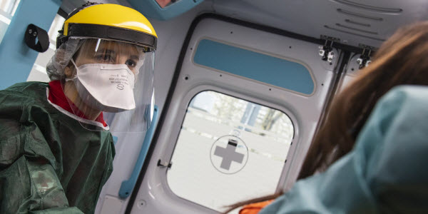 medical staff wearing PPE in ambulance with patient