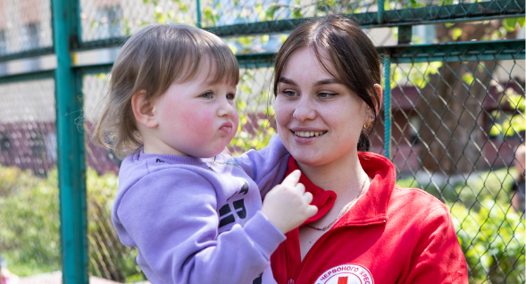 A Red Cross worker holding a child