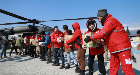Red Crescent workers unloading supplies from a helicopter
