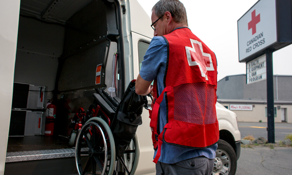 Canadian Red Cross worker loads a wheelchair into Red Cross van for delivery.