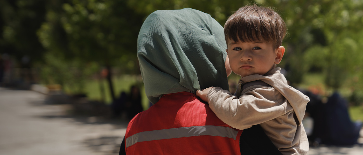 An Afghan child is held by a Red Cross/Red Crescent worker.