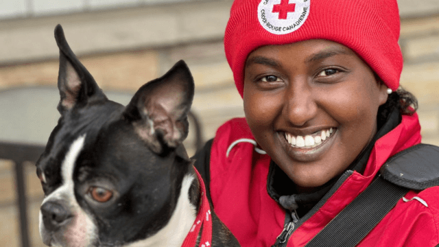A face-to-face fundraising Red Cross volunteer smiling and holding a dog