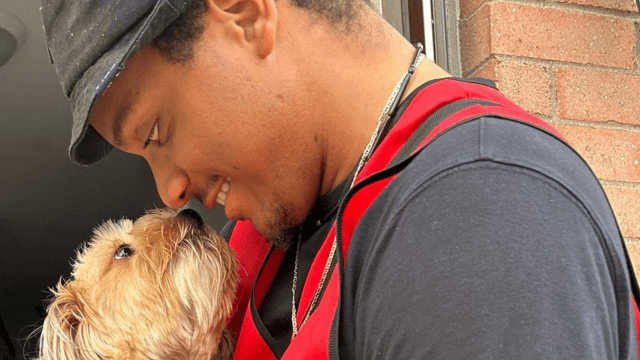 A face-to-face fundraising Red Cross volunteer sharing a nose-to-nose greeting with a dog