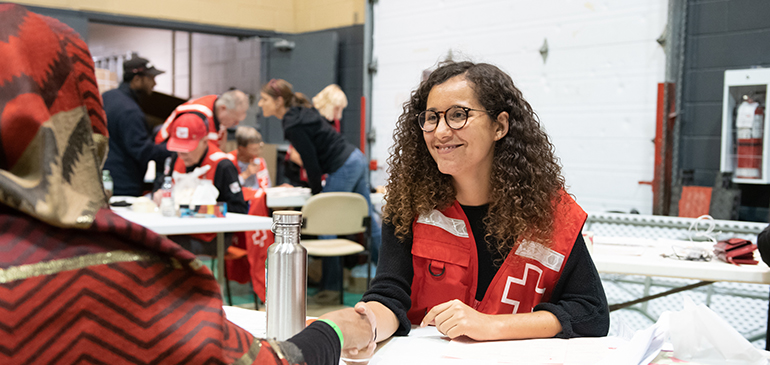 A Canadian Red Cross employee shaking hands with a woman at a shelter
