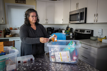 An older woman puts medical supplies in a plastic tub