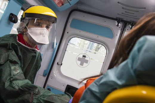 medical staff wearing PPE in the back of ambulance with patient