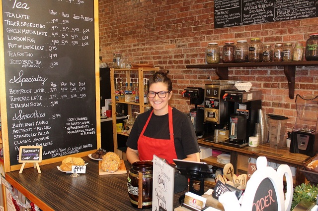 woman behind the counter of a coffee shop, smiling