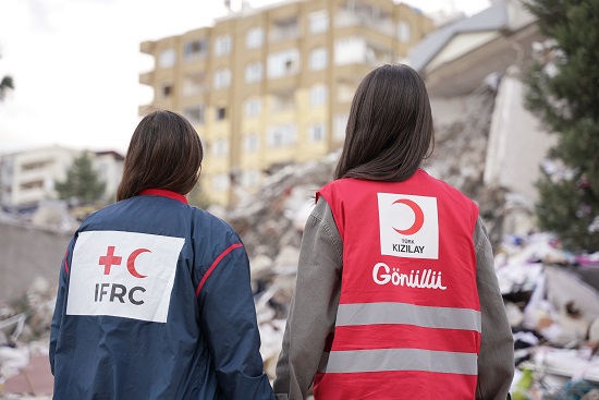 Two Red Crescent volunteers looking at the devastation