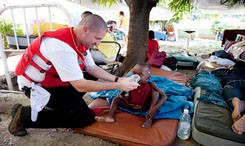 A Red Cross volunteer provides hydration to a child.