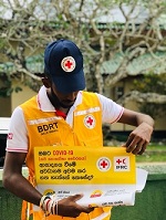young man wearing a Red Cross Vest holding a sign in Sinhala