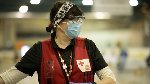 A Red Cross volunteer wearing gloves and mask in the middle of work.