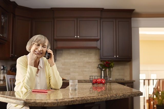 elderly woman sitting in her kitchen, talking on her phone