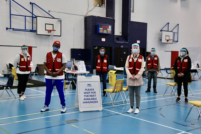 Red Cross volunteers wearing PPE in a gym, 6 feet apart