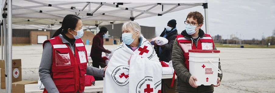 Two Red Cross volunteers helping a senior lady