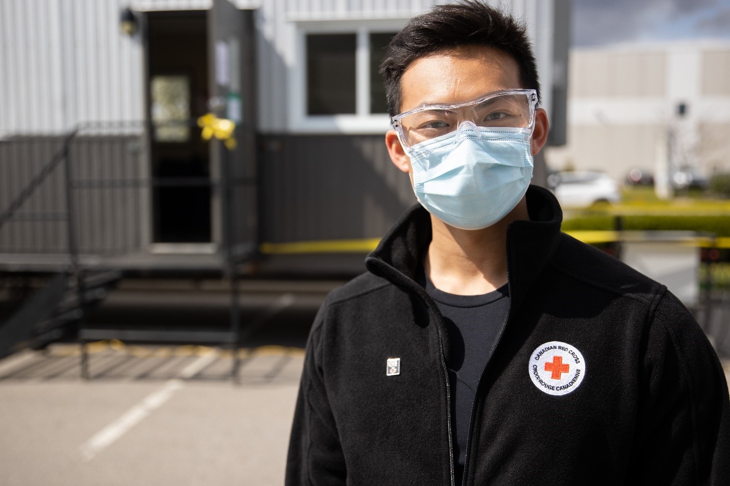 Red Cross worker outside wearing medical mask and protective eyewear