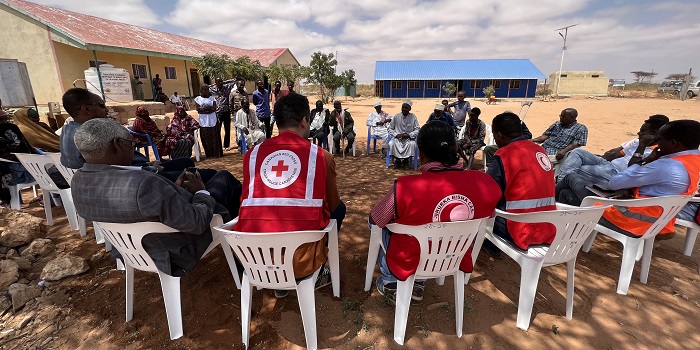 A group of Red Cross society members sitting in chairs 