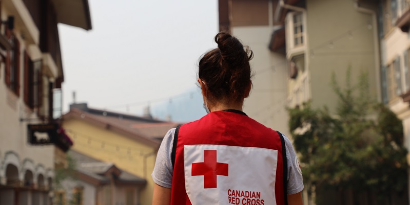 Woman in a Red Cross vest with her back facing the camera displaying the logo