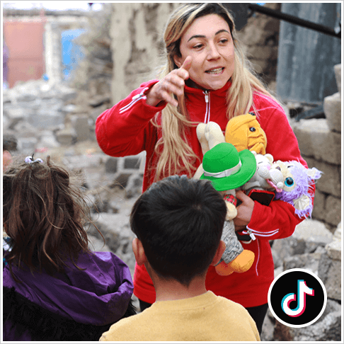 A Turkish Red Crescent staff member holding stuffed animals ready to hand them over to kids in Turke