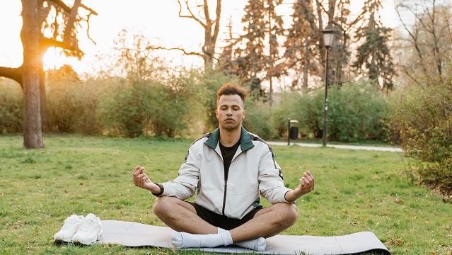 man meditating on a mat outside