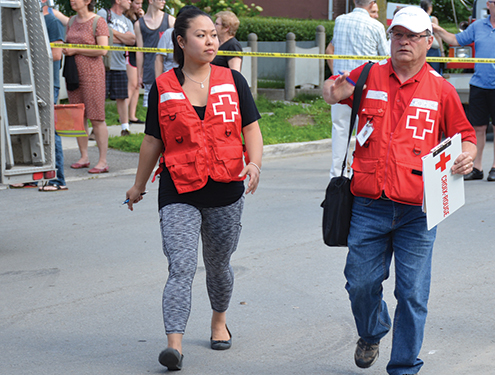 Two Red Cross volunteers walk and talk together outside.
