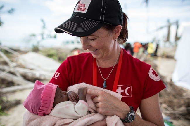 Canadian Red Cross aid worker holding a baby outdoors