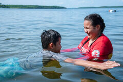 girl in lake teaching boy how to float