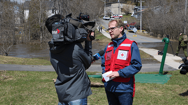  A Canadian Red Cross representative wearing a red vest speaks to a Global News cameraman.