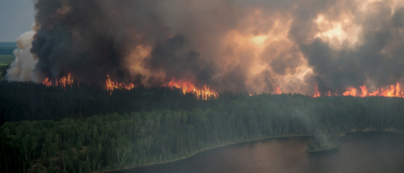 An aerial view of a wildfire raging near a lake