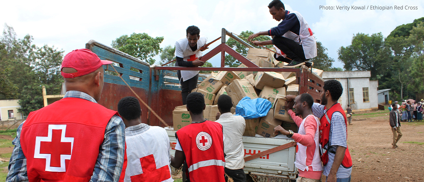 Red Cross staff and volunteers unload supplies from a truck.