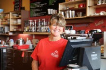 Woman smiling behind bar wearing red tee shirt