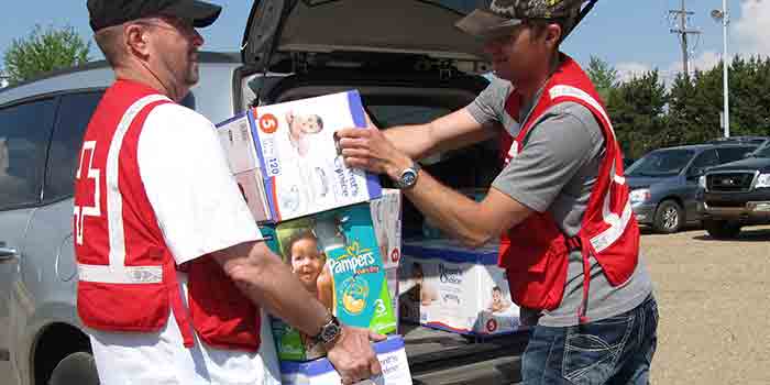 Two male Red Cross volunteers unloading diapers.