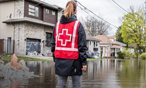 Red Cross volunteer wading through community that was hit by a flood