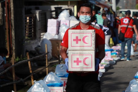 A Red Cross volunteer holds boxes with supplies.