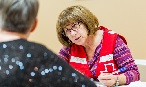 A Canadian Red Cross volunteer sits at a table and helps register someone