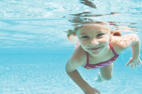 Young child swimming underwater, smiling
