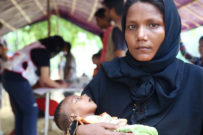 A woman holding her baby while waiting at a mobile clinic